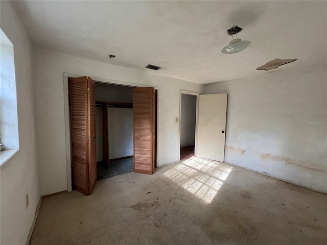 unfurnished bedroom featuring light colored carpet and a closet