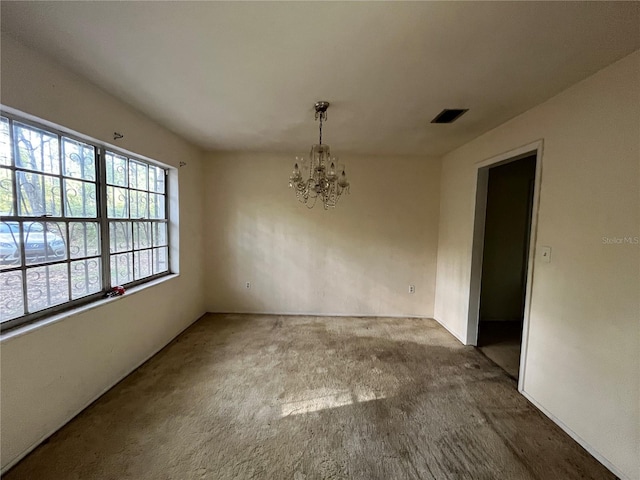 carpeted spare room featuring a chandelier