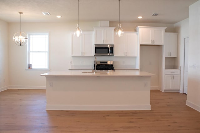 kitchen featuring appliances with stainless steel finishes, light wood-type flooring, and a kitchen island with sink