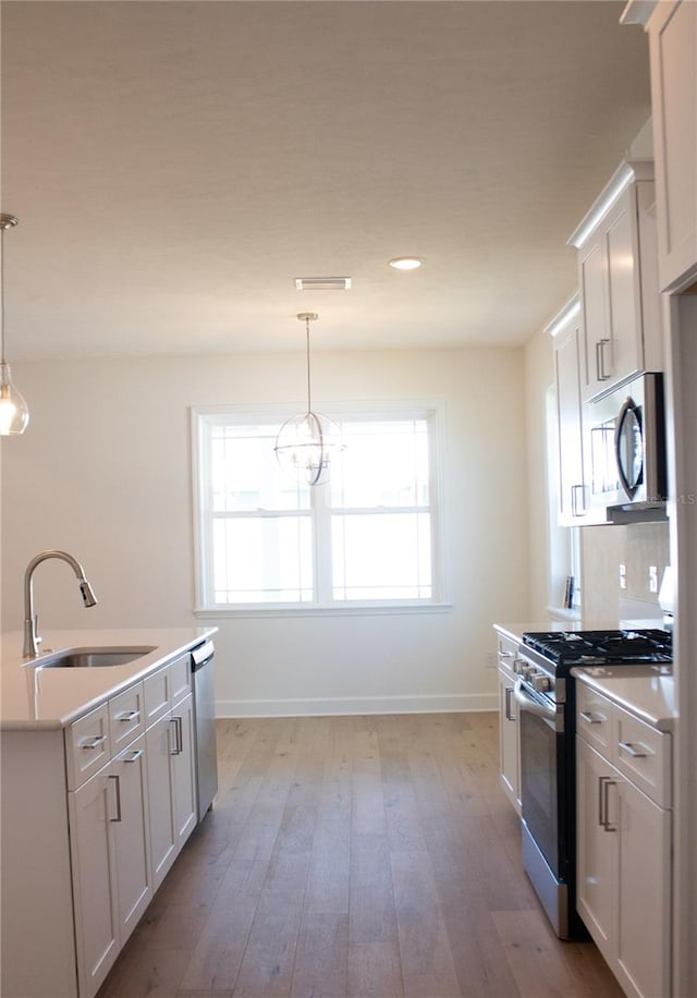 kitchen with white cabinetry, sink, pendant lighting, and appliances with stainless steel finishes