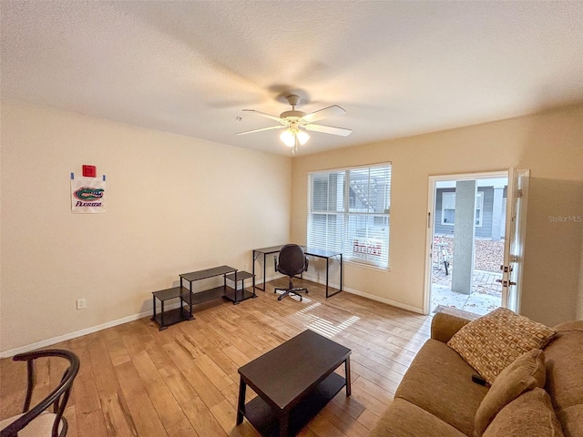 living room with a textured ceiling, ceiling fan, and light hardwood / wood-style flooring