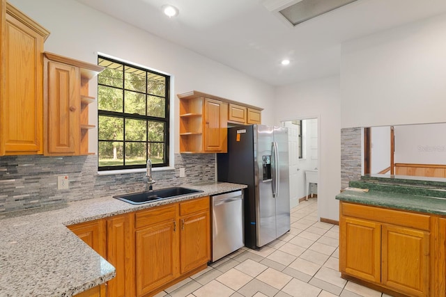 kitchen with backsplash, light stone counters, sink, and appliances with stainless steel finishes