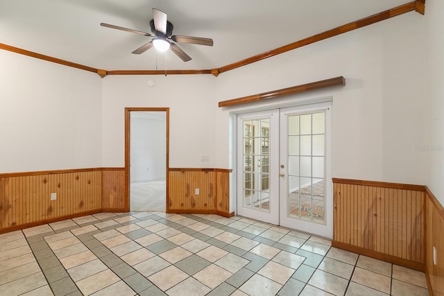 tiled spare room with ornamental molding, french doors, ceiling fan, and wooden walls