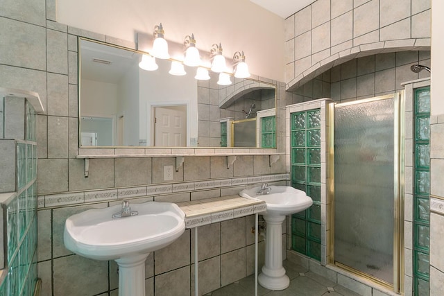 bathroom with tile walls, backsplash, an enclosed shower, and tile patterned flooring