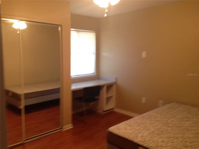 unfurnished bedroom featuring wood-type flooring, ceiling fan, and a closet