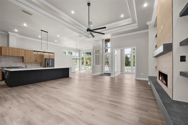 unfurnished living room with a tile fireplace, crown molding, sink, and light hardwood / wood-style floors