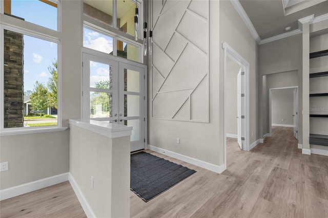 entrance foyer featuring crown molding, french doors, a healthy amount of sunlight, and light wood-type flooring