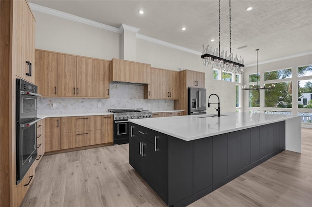 kitchen with decorative light fixtures, high quality appliances, a large island with sink, and tasteful backsplash