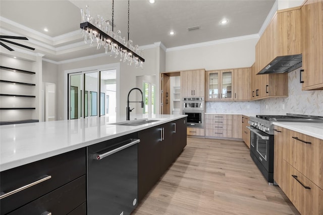 kitchen featuring sink, wall chimney exhaust hood, appliances with stainless steel finishes, tasteful backsplash, and decorative light fixtures