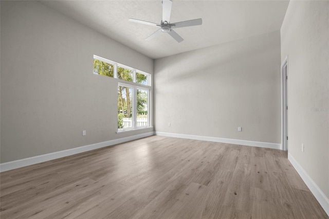 unfurnished room with ceiling fan, light wood-type flooring, and a high ceiling