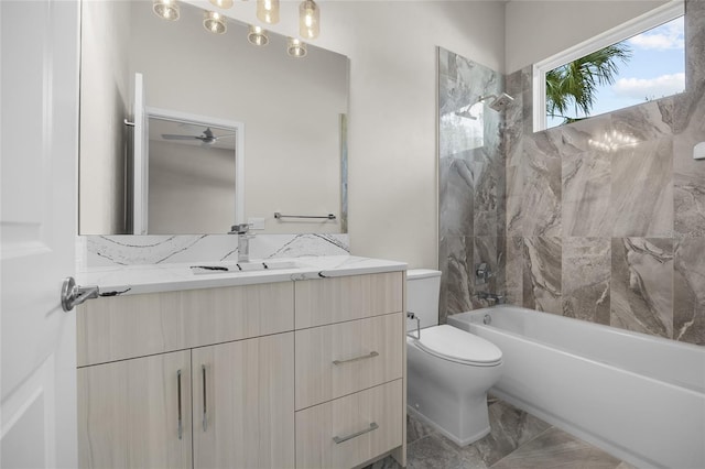 full bathroom with ceiling fan, toilet, tiled shower / bath, and vanity