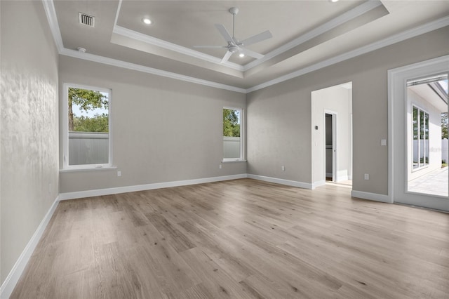 empty room featuring ceiling fan, light hardwood / wood-style floors, a raised ceiling, and crown molding