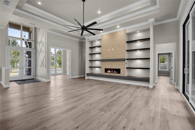 unfurnished living room featuring a high ceiling, french doors, a raised ceiling, built in shelves, and a wealth of natural light