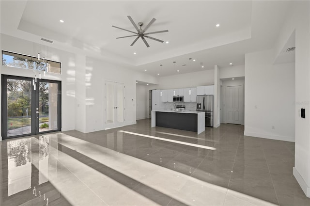 tiled living room with french doors, ceiling fan, and a raised ceiling