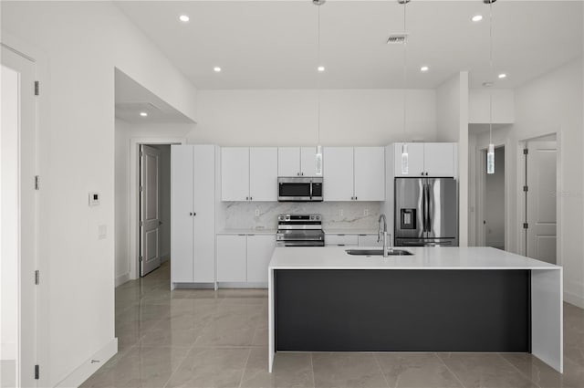 kitchen with stainless steel appliances, sink, white cabinetry, and a kitchen island with sink