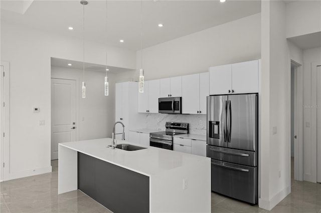 kitchen featuring an island with sink, pendant lighting, sink, white cabinets, and appliances with stainless steel finishes