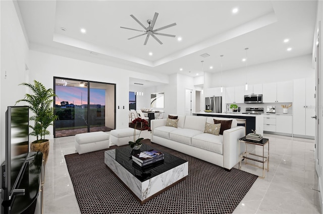 tiled living room with a towering ceiling, ceiling fan, and a raised ceiling