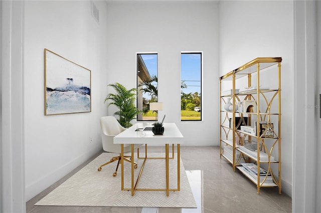 tiled home office featuring a healthy amount of sunlight and a towering ceiling