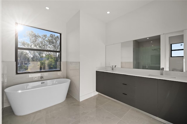 bathroom featuring tile walls, tile floors, a bath, and double sink vanity