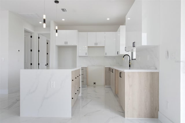 kitchen featuring tasteful backsplash, white cabinetry, light tile floors, sink, and hanging light fixtures