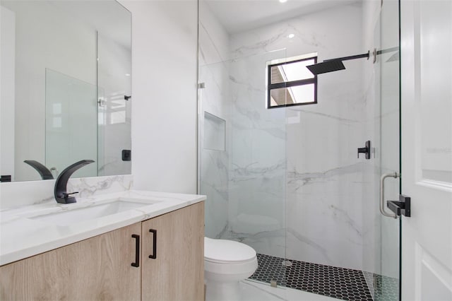 bathroom with oversized vanity, toilet, and a shower with door