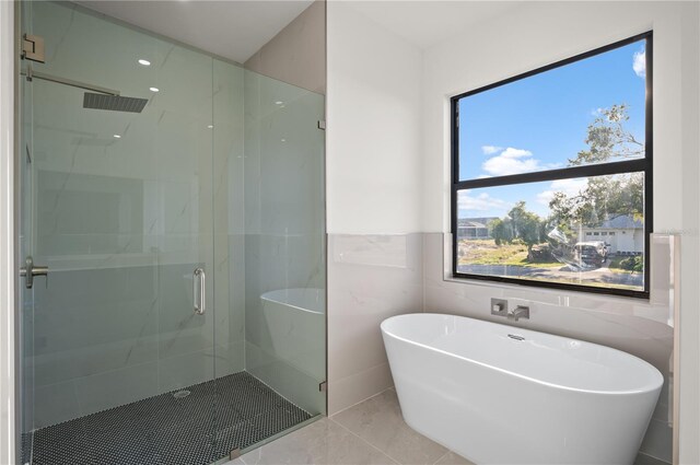 bathroom with tile walls, tile floors, and shower with separate bathtub