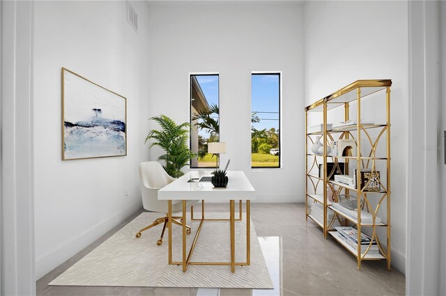 tiled office featuring a high ceiling and a healthy amount of sunlight