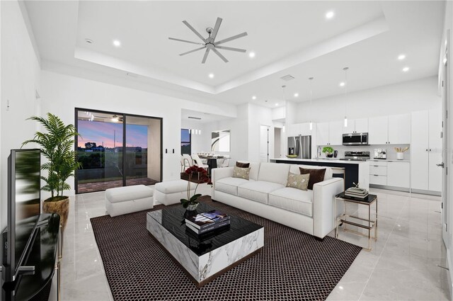 tiled living room featuring ceiling fan, a high ceiling, and a tray ceiling