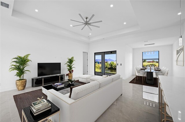 living room with a raised ceiling, french doors, ceiling fan, and light tile floors