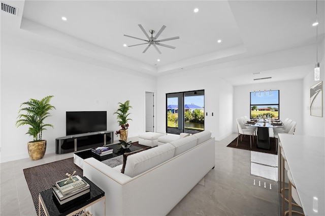 living room featuring visible vents, a raised ceiling, and recessed lighting