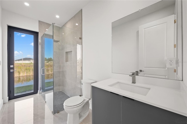 bathroom featuring tile flooring, a water view, a shower with door, toilet, and large vanity