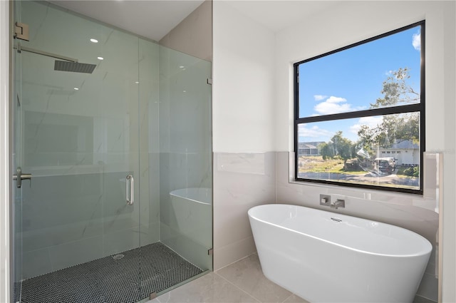 full bath featuring a soaking tub, tile walls, a marble finish shower, and tile patterned floors