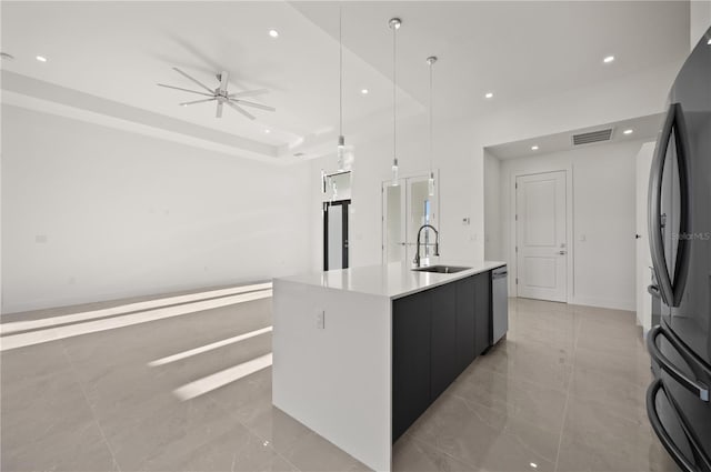 kitchen with decorative light fixtures, light countertops, open floor plan, a kitchen island with sink, and a sink