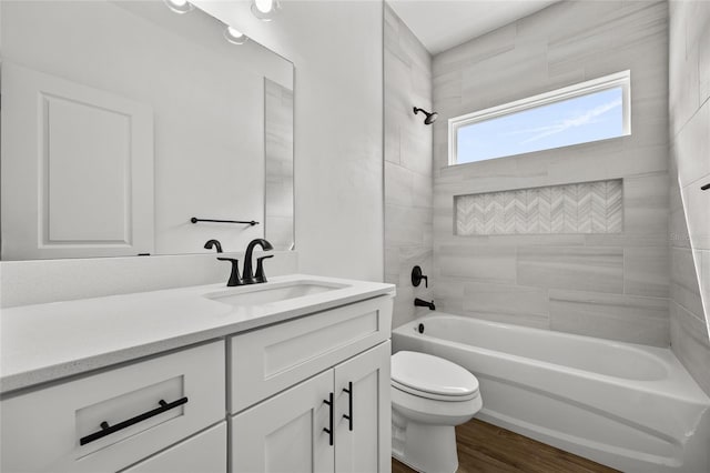 full bathroom featuring hardwood / wood-style floors, vanity, tiled shower / bath combo, and toilet