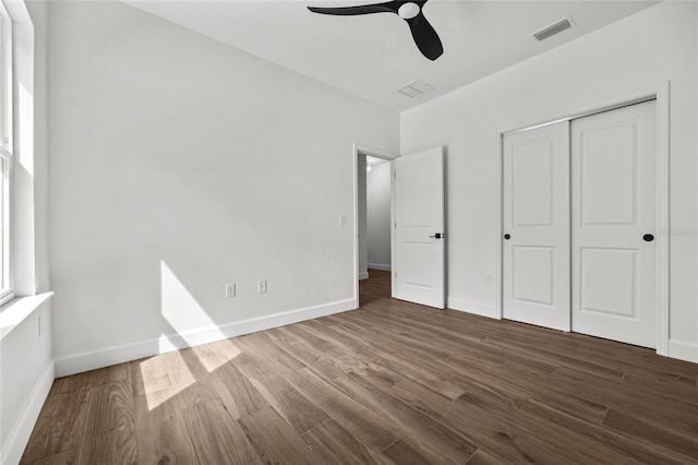 unfurnished bedroom with ceiling fan, a closet, and dark hardwood / wood-style floors