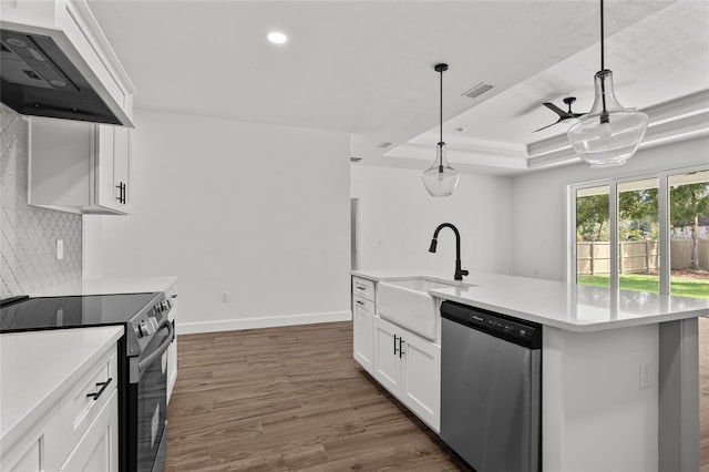 kitchen featuring pendant lighting, white cabinets, appliances with stainless steel finishes, and wall chimney range hood