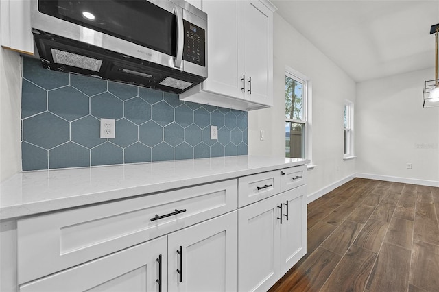 kitchen featuring light stone counters, white cabinets, pendant lighting, and dark hardwood / wood-style flooring