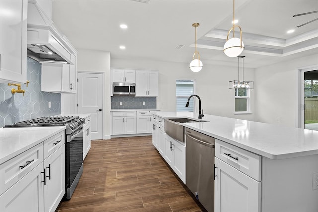 kitchen with an island with sink, sink, stainless steel appliances, and white cabinets