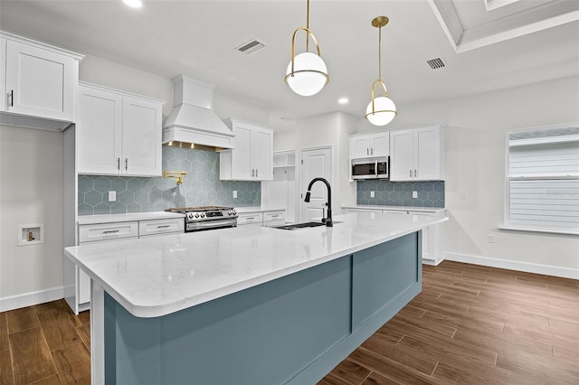 kitchen with stainless steel appliances, white cabinets, decorative light fixtures, and custom exhaust hood