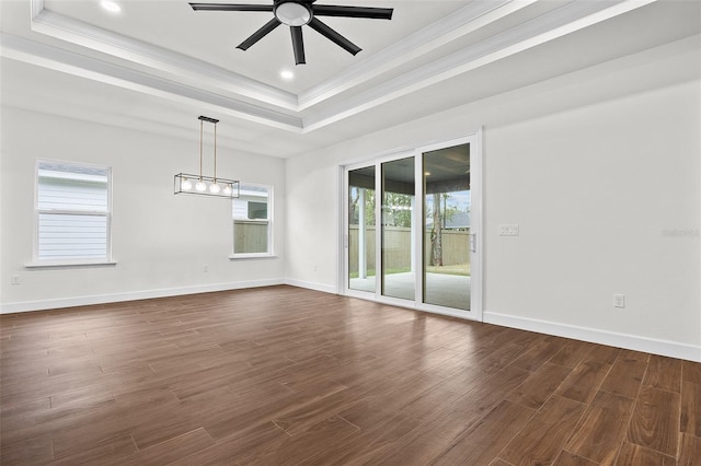 spare room featuring a tray ceiling, ceiling fan, plenty of natural light, and dark wood-type flooring