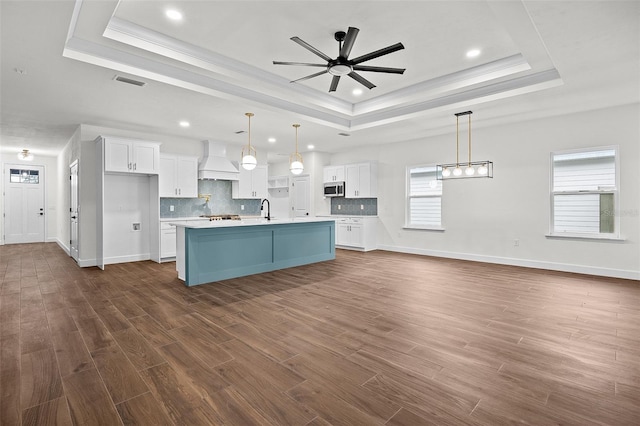 kitchen with a raised ceiling, ceiling fan, and stainless steel appliances