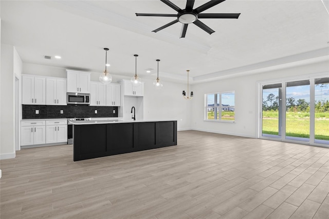 kitchen featuring hanging light fixtures, a center island with sink, white cabinets, ceiling fan with notable chandelier, and appliances with stainless steel finishes