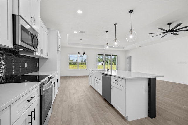 kitchen with white cabinets, stainless steel appliances, and an island with sink