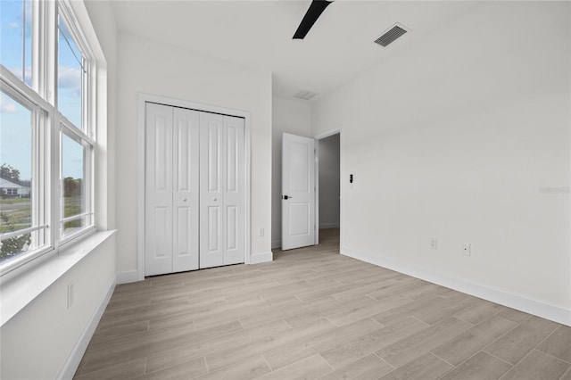 unfurnished bedroom with ceiling fan, multiple windows, and a closet