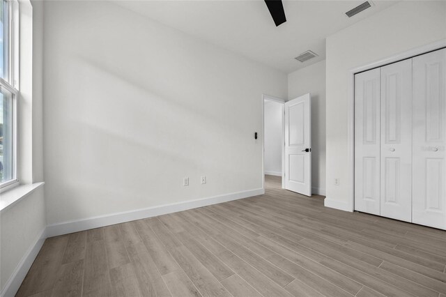 unfurnished bedroom with ceiling fan, light hardwood / wood-style flooring, and a closet