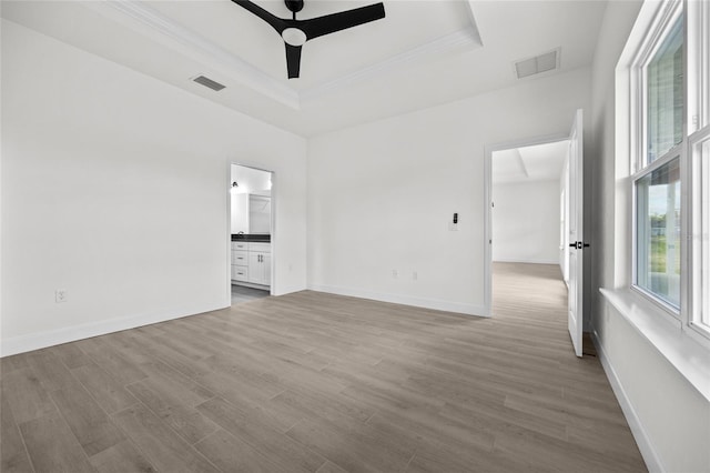 empty room with a tray ceiling, ceiling fan, and wood-type flooring