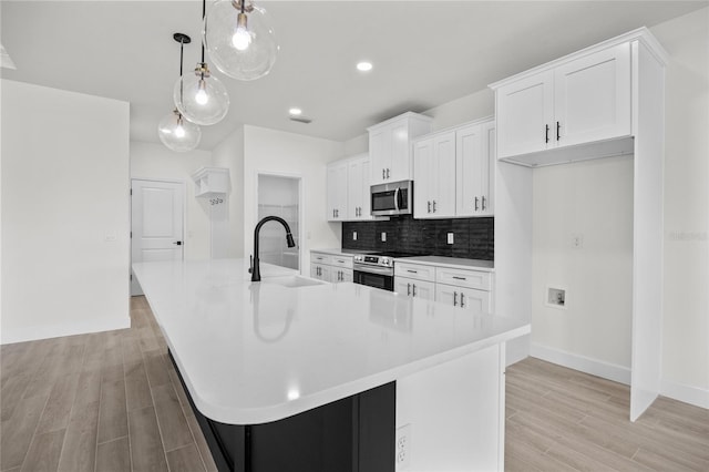 kitchen with stainless steel appliances, pendant lighting, sink, and a spacious island