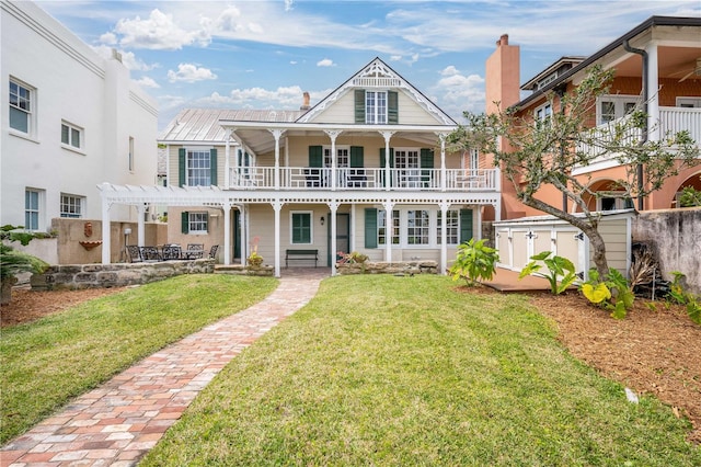 view of front facade with a balcony, a pergola, and a front yard