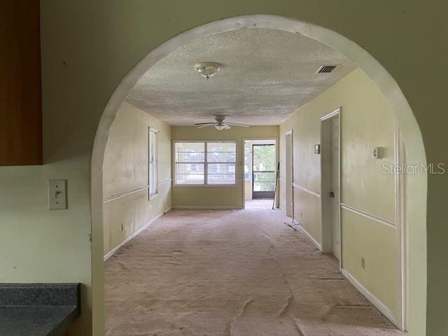 hall with light colored carpet and a textured ceiling