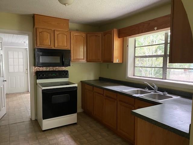 kitchen with a textured ceiling, tile floors, sink, and white range with electric stovetop